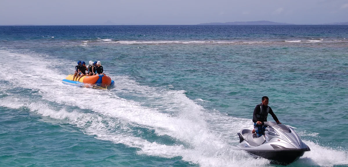 A jet ski towing visitors across clear Okinawan water
